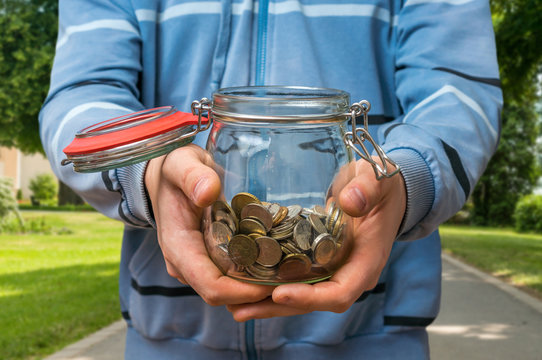 Man In Blue Sweatshirt Holding Money Jar With Coins