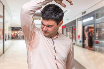 Man with sweating under armpit in shopping center