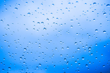 Water drops on glass with blue sky for background.	