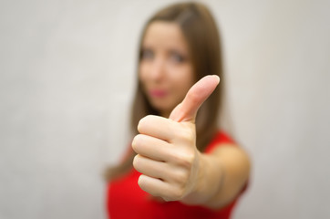 Young smiling woman in red dress showing Thumbs up sign by her hand. Success. Approving gesture. Confirmation.