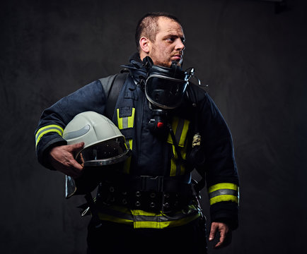 Firefighter dressed in uniform holds safety helmet.