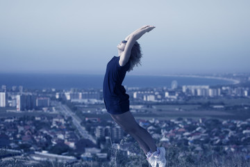 Girl jumping on the lake on the background of the sea and the city