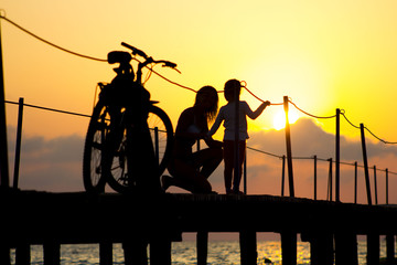 Mother and daughter embracing on a wooden bridge sunset. style abstract shadows.silhouette