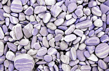 Abstract purple dry round stones background. At the beach. Sea pebbles and gravel style. Top view. Close up.