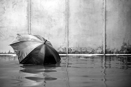 Concept umbrella floating. Flooded on street. .Waiting for help me after the rain. Black and white colors. Close up.
