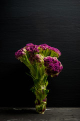 Red cauliflower on the black wooden background. Selective focus. Shallow depth of field.