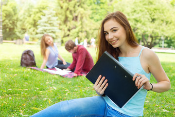 Fototapeta premium Happy student woman. Young female holding a folder with documents to study. Student life everyday.