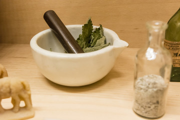 Mortar with herb and glass with ingredients.