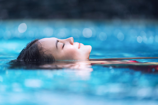 Young asian woman relaxing in swimming pool at spa resort.