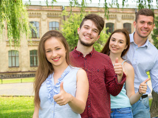 Group of young people students at the background of the building of the university. Two guys and two girls, selective focus on the penny group of people.
