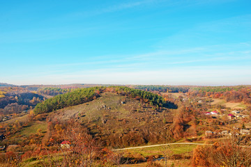 View on the beautiful colorful autumn landscape of the hills with trees and greenfields in the countryside