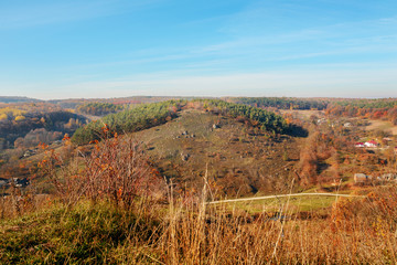 View on the beautiful colorful autumn landscape of the hills with trees and greenfields in the countryside