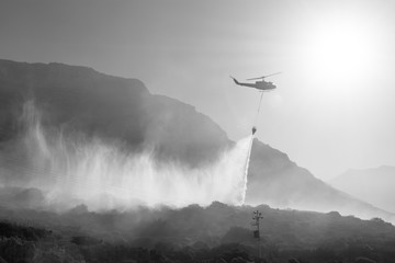 A firefighting Bell Huey helicopter dumps water onto a bush fire in Cape Town, South Africa.