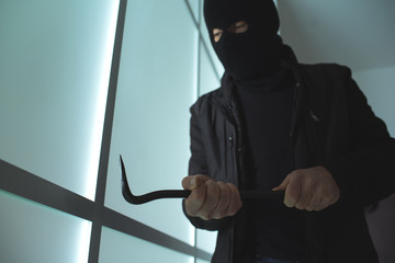 Burglar using a crowbar to break into a house