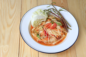Papaya Salad with Carrot, Lentils, Tomato, Dried Shrimp, Chilli, in a White plate on wooden background. Thai style food.