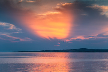 Sunset at sea with the rays of the sun through the clouds in beautiful colors. Island Vir on Adriatic Sea, Croatia, Europe.