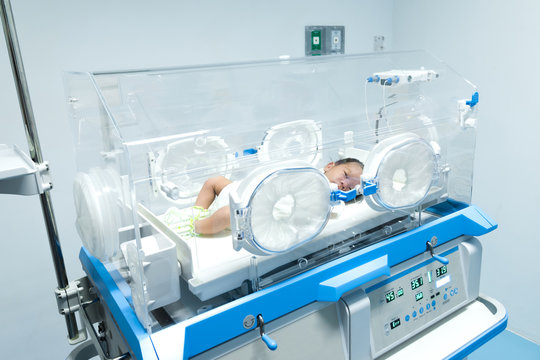 Infant In Incubator Machine Maintain Healthy Environment For Newborn Premature Sick Babies Neonatal Intensive Care Unit.