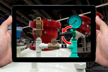 Industrial 4.0 concept. Augmented reality glasses service. Engineering use tablet to monitoring and maintenance by visually overlaying the procedure in smart factory background