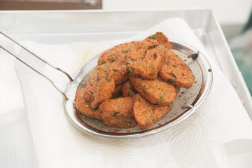 Cooked fried fish cake in a ladle