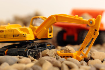 Naklejka premium Toy excavator and tipper truck on gravel