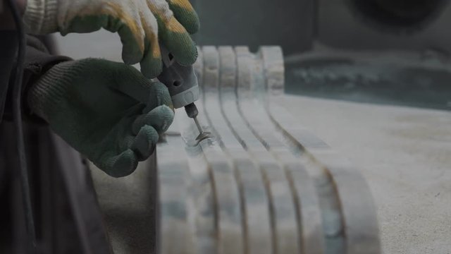 Worker cutting stone plate with professional tools, creates an ornament of the future fireplace