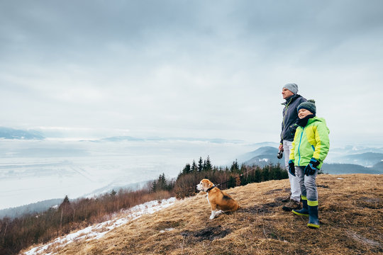 Early spring time - father with son walk with dog on mountain hills