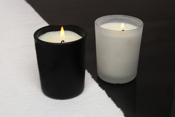 Fototapeta na wymiar White and black candles. Two burning candles.