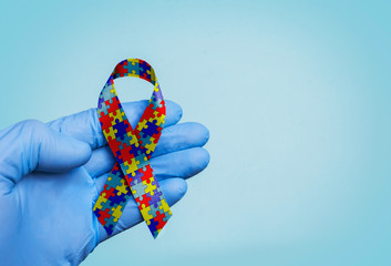 World Autism awareness and pride day with Puzzle pattern ribbon. The doctor's hand in gloves