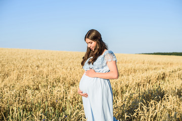 Outdoor portrait of unrecognizable young pregnant woman in the field. beautiful pregnant woman with big belly relaxing in the summer nature meadow