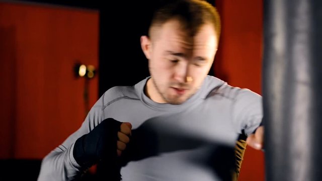 A boxer throws heavy punches on a boxing bag. 