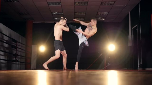 A fighter throws down his opponent with one well-placed kick. 