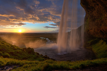 Blick hinter dem Wasserfall zum Sonnenuntergang