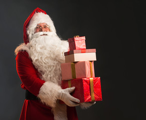 Santa Claus holding a presents, over a dark background © Tijana