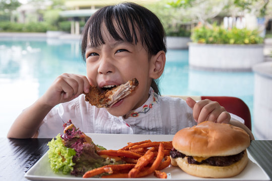 Asian Little Chinese Girl Eating Burger and Fried chicken