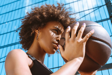 african-american woman adjusting aim with basketball