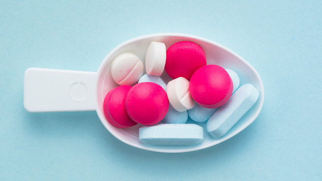 colorful color pills in the tablespoon on blue background