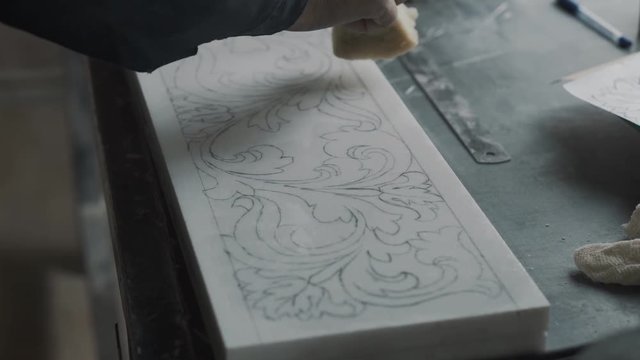 Employee uses a paralon sponge to apply a fixing varnish on the surface of the marble slab, doing this to fix the pattern
