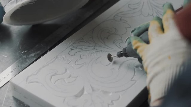 Engraver cut out the pattern in the marble slab, the stencil is applied in advance, making one part of the marble fireplace