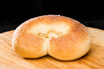 close-up of fresh sweet delicious homemade pretzel on round wooden board on dark background