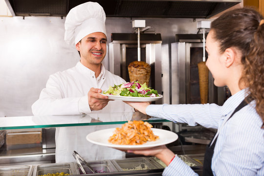 Positive waitress receiving order from chef