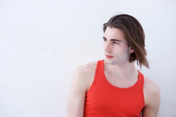 Close up portrait of serious sporty young man standing by white wall