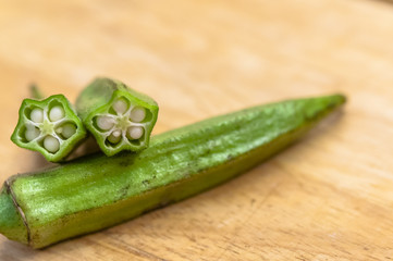 Close-up of pile of organic okra on wood . Okra fruits at cutting board