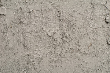 White-gray surface of a wall with cracked paint, plaster, close-up 