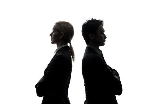 Silhouettes of caucasian businesswoman and asian businessman standing back to back.
