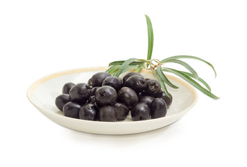 Black olives on saucer and olive branch closeup