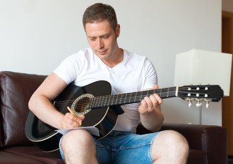 Handsome man compose a song on the guitar.