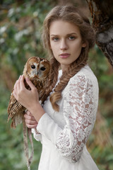 Beautiful romantic woman with an owl. The bird sits on her hand.