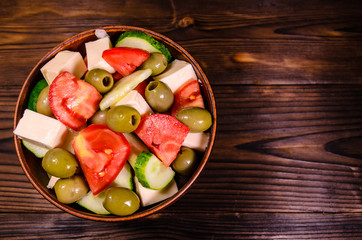 Greek salad in a bowl on wooden table. Top view