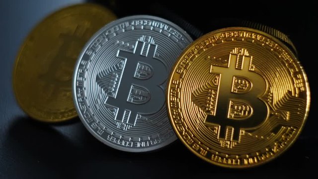 Gold and silver bitcoins lie on a black background. Change of focus
