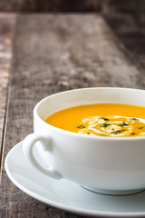 Pumpkin soup in white bowl on wooden table